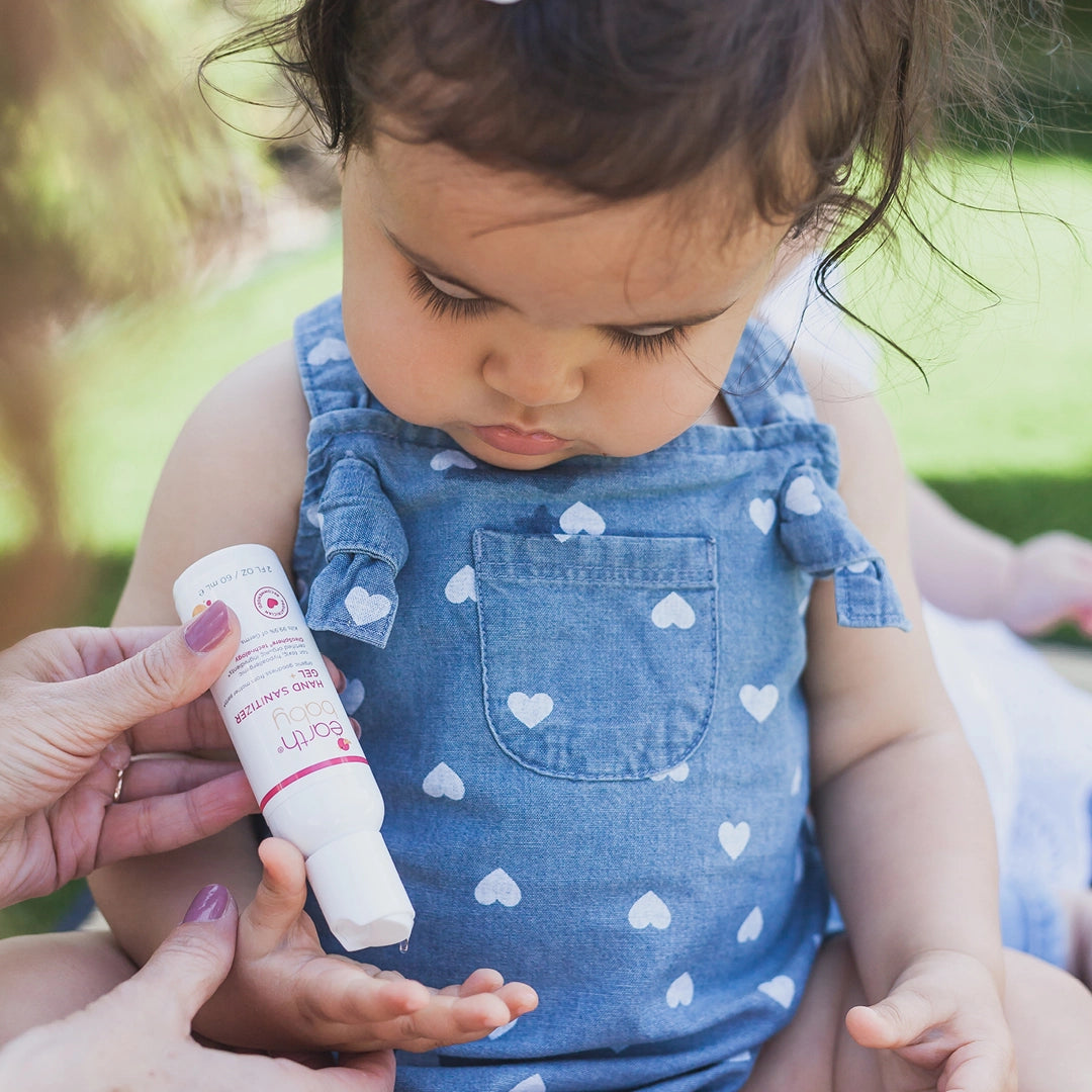 Wellness & Sanitizers Collection. Photo of baby girl having sanitizer applied to her hand.