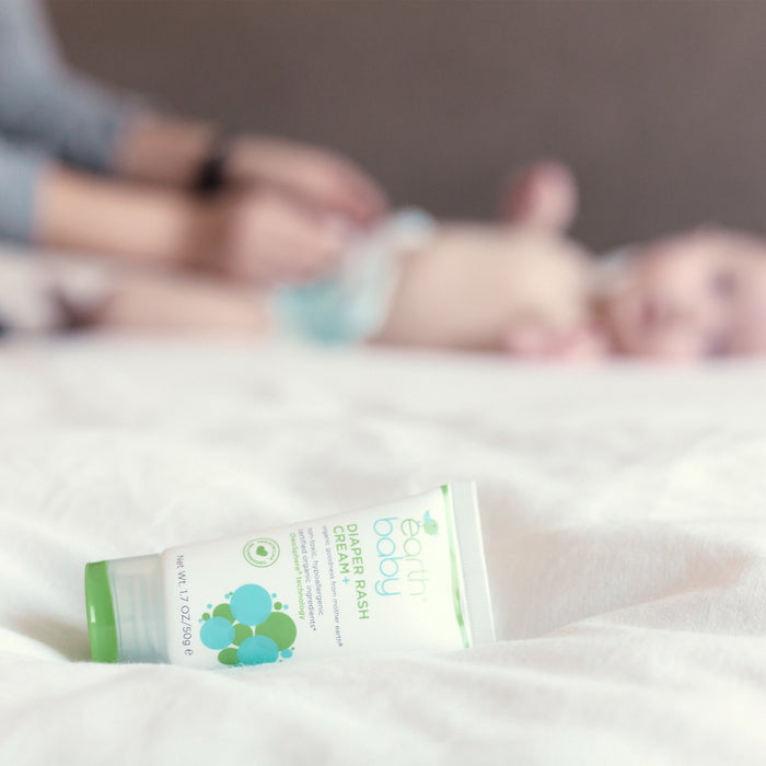 Non-Toxic, Hypoallergenic Diaper Rash Cream on bed with baby getting a diaper change in the background