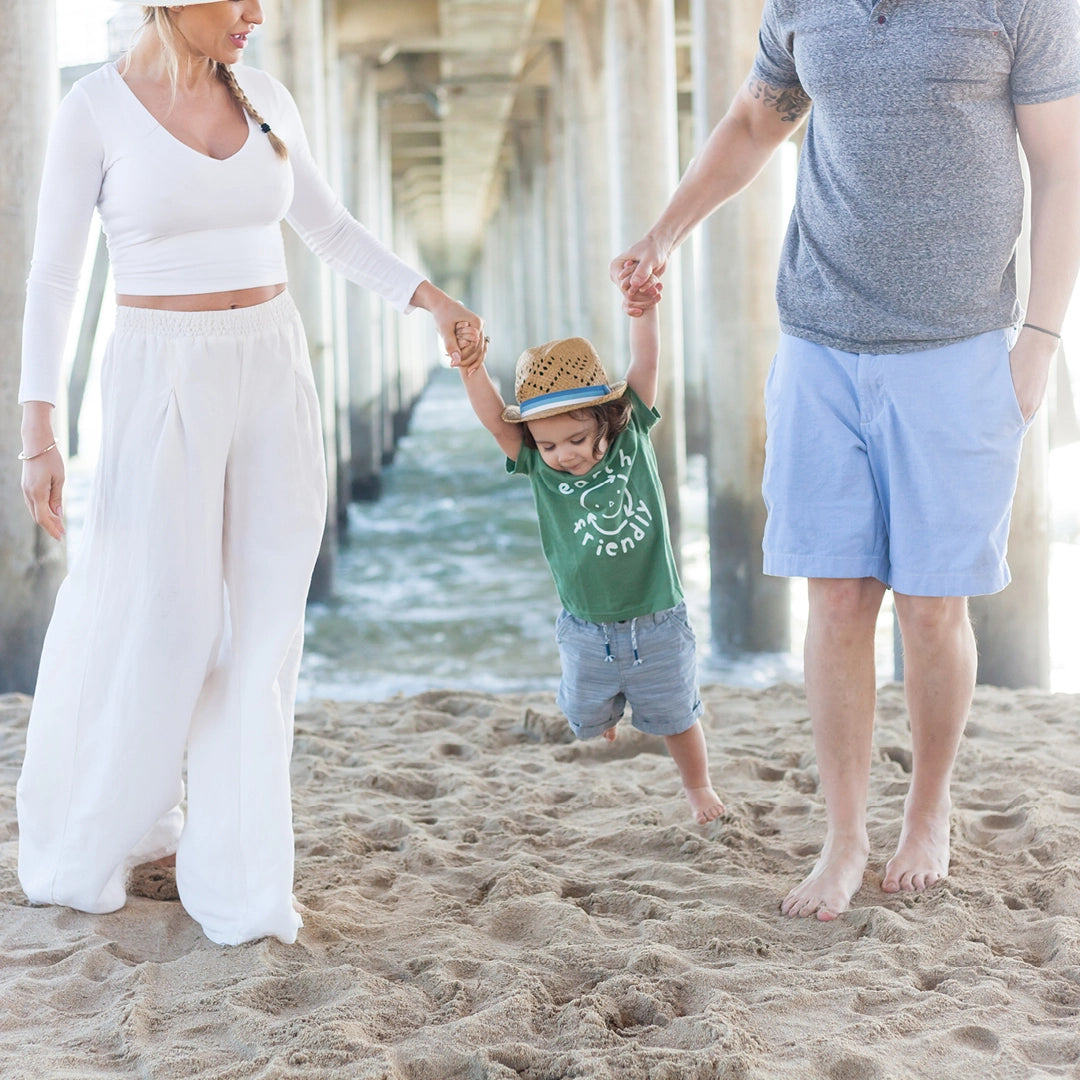 Travel Collection. Photo of mom and dad holding up toddler boy on the beach.